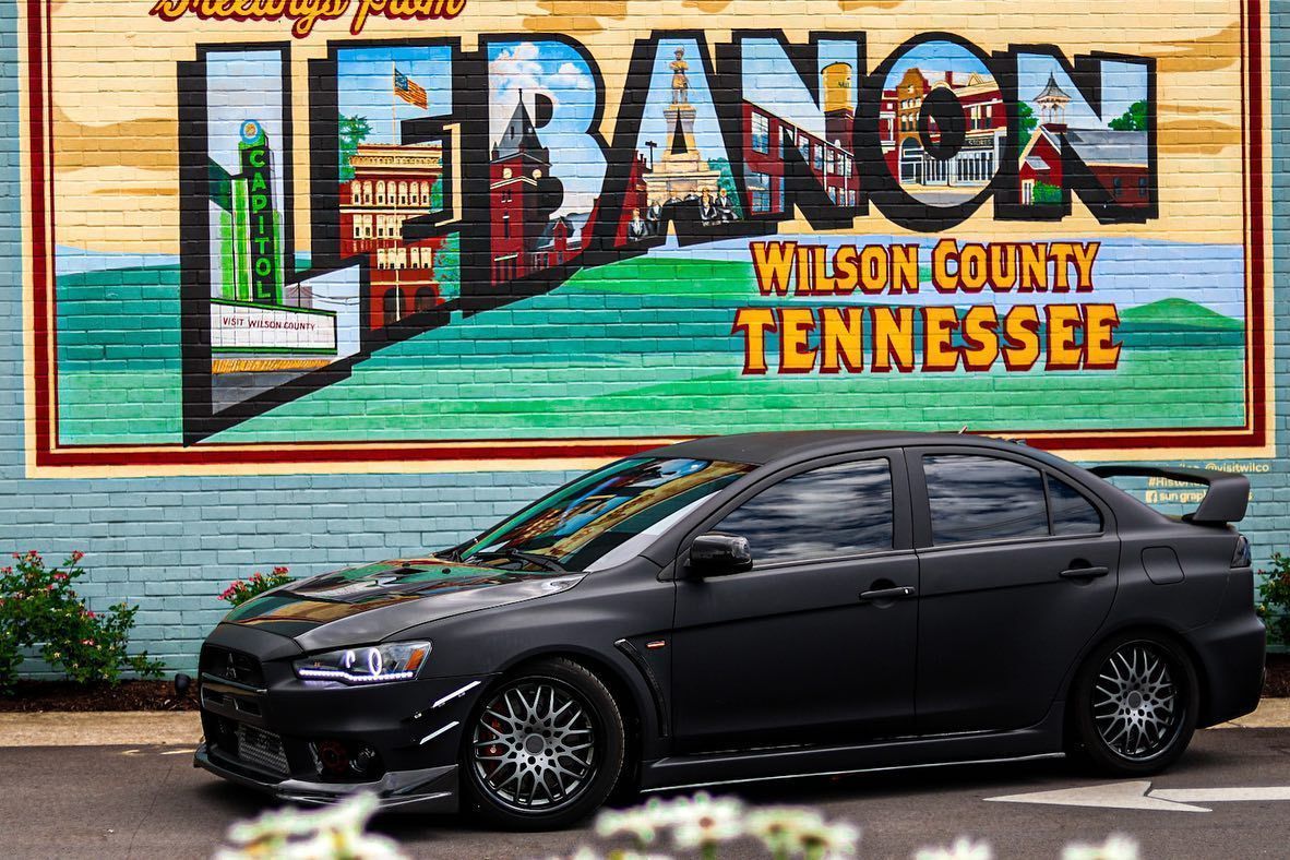 Black sedan parked before a mural reading “Lebanon, Wilson County, Tennessee.”