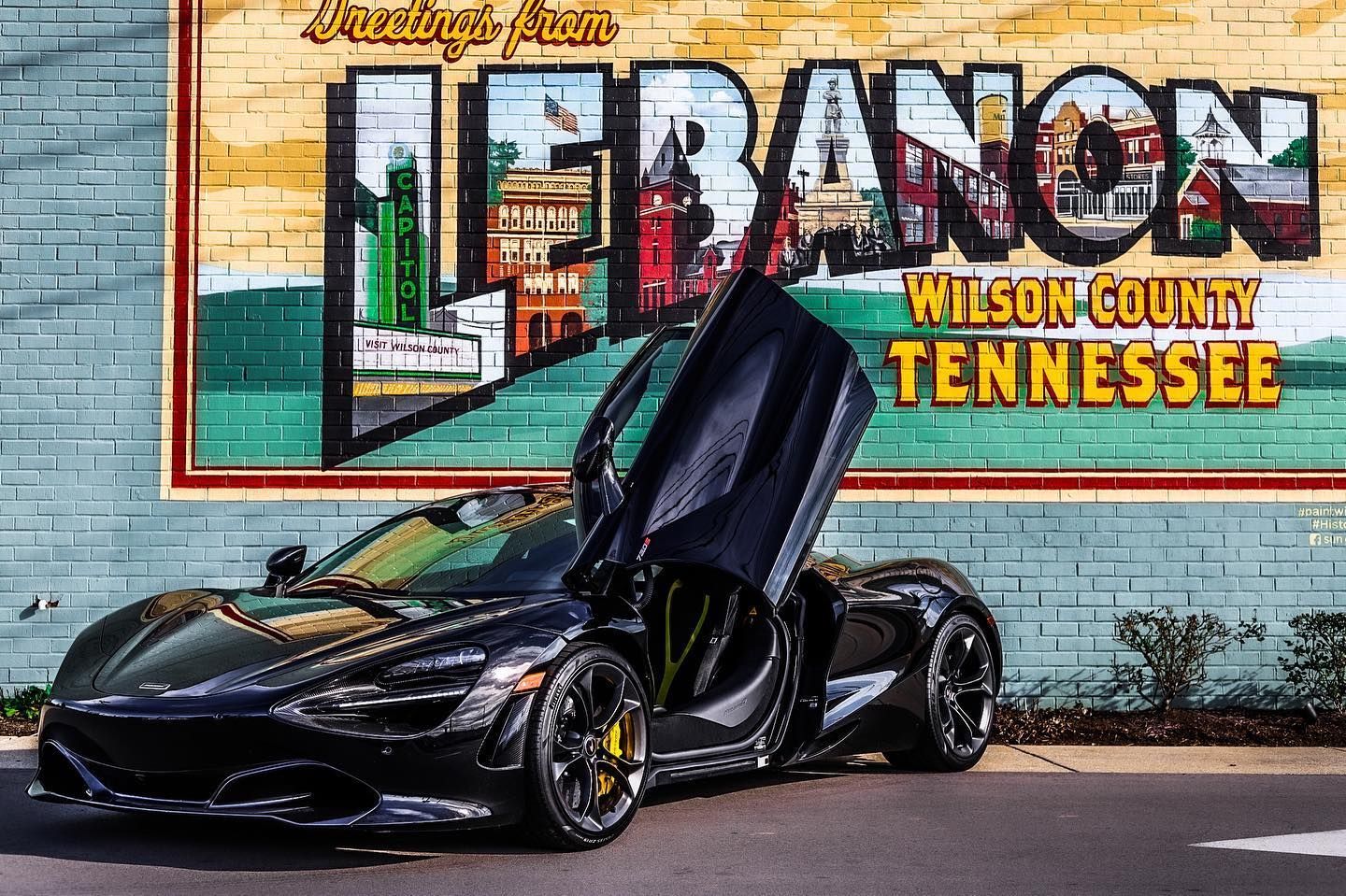 Black sports car with door open in front of a colorful Lebanon, Wilson County, Tennessee mural