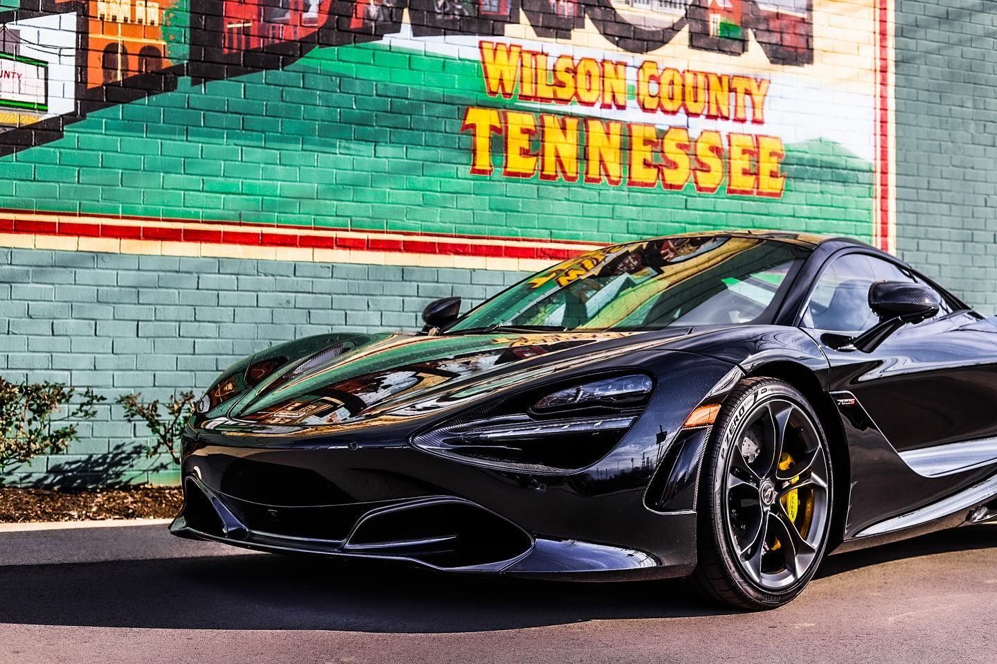 Black sports car parked in front of a mural reading “Wilson County Tennessee”