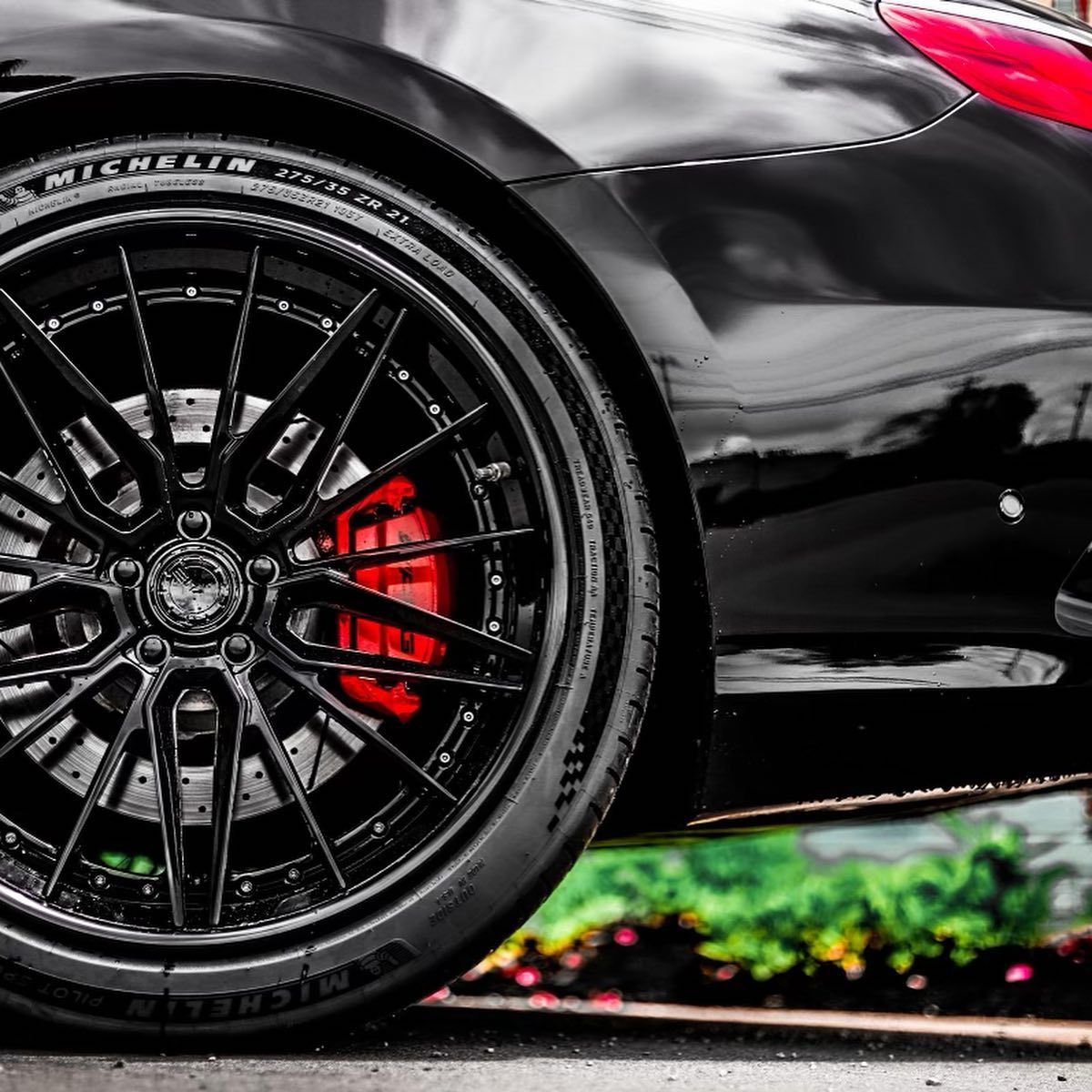 Close-up of a black sports car wheel with red brake caliper and glossy bodywork