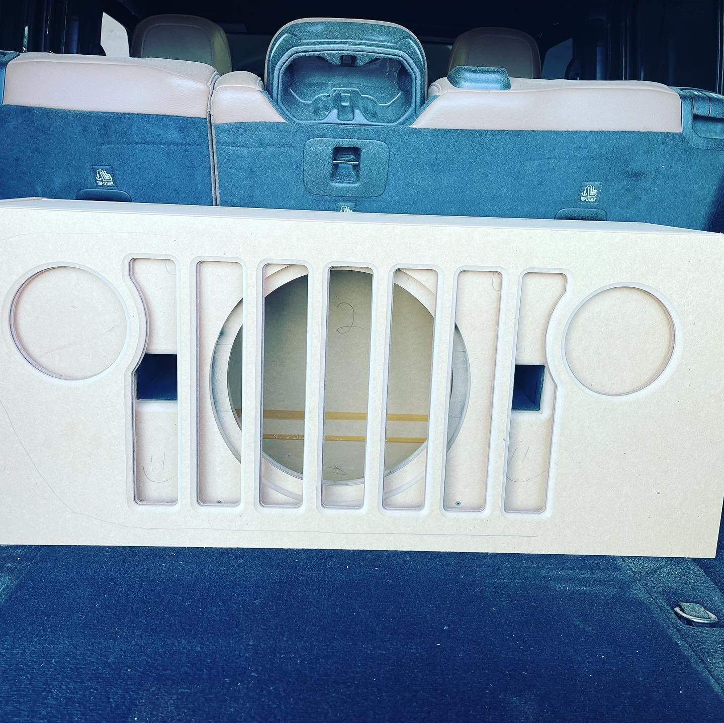 White plastic grille on a blue seat back, with circular cutouts and vertical slats.