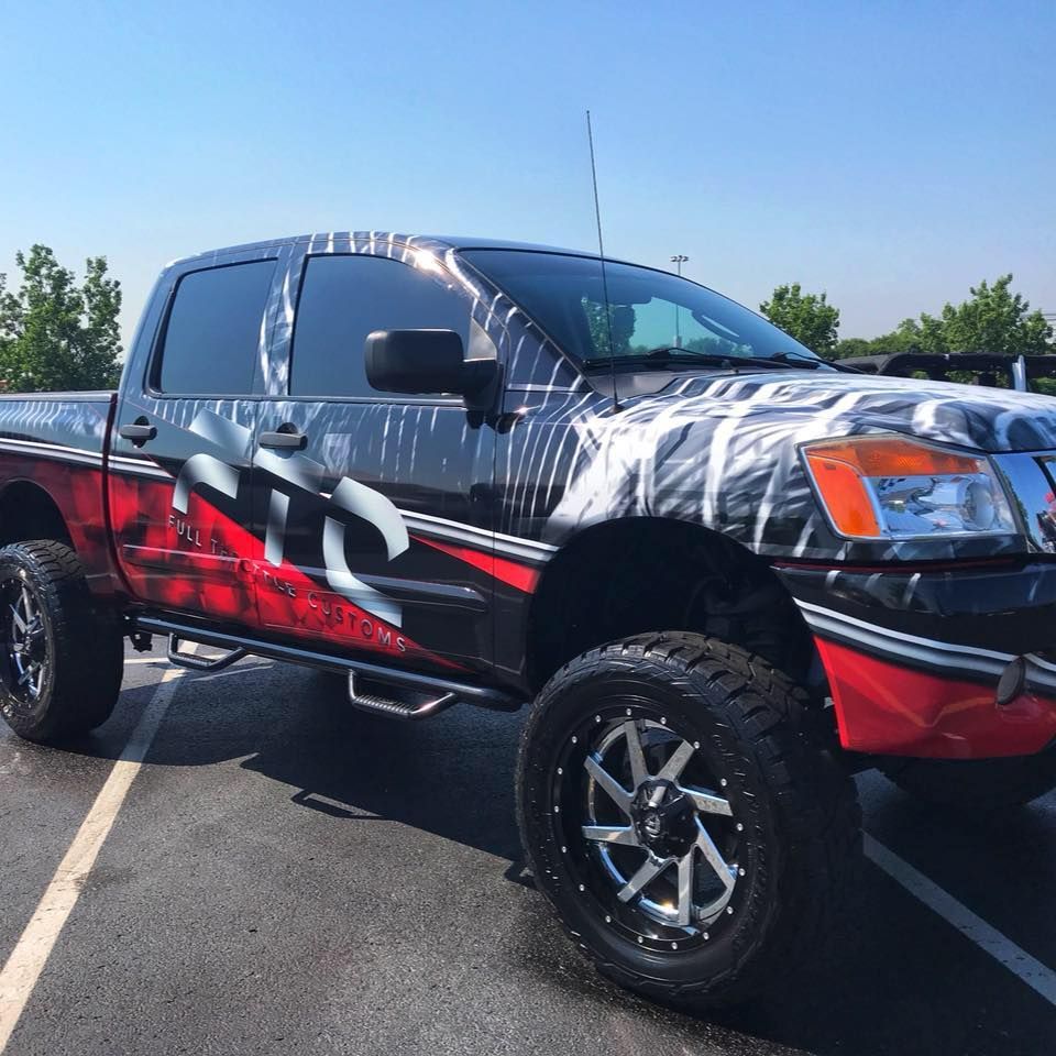 Customized black pickup truck with red and white graphics parked in a lot