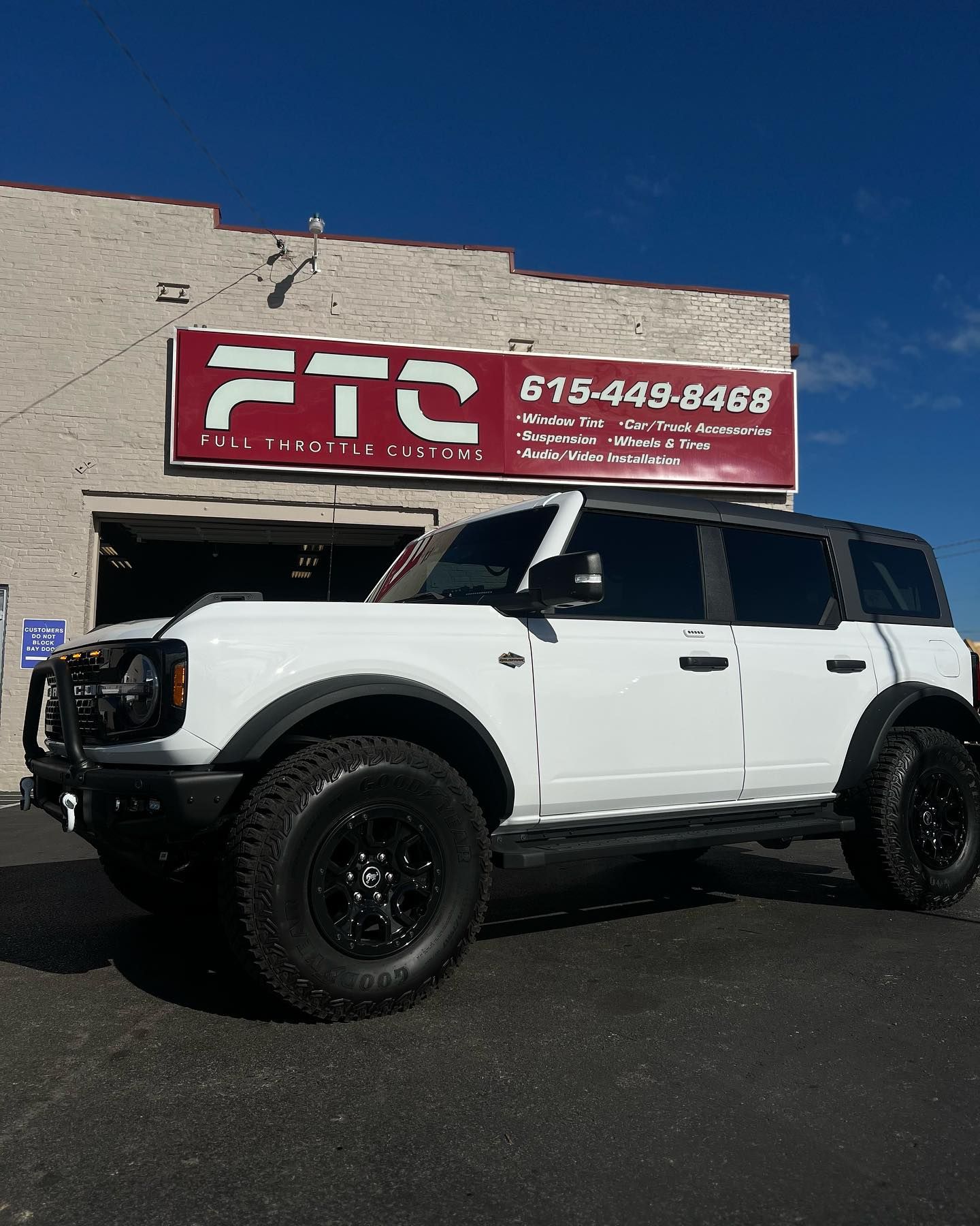 White off-road SUV parked outside an FTC sign on a sunny day