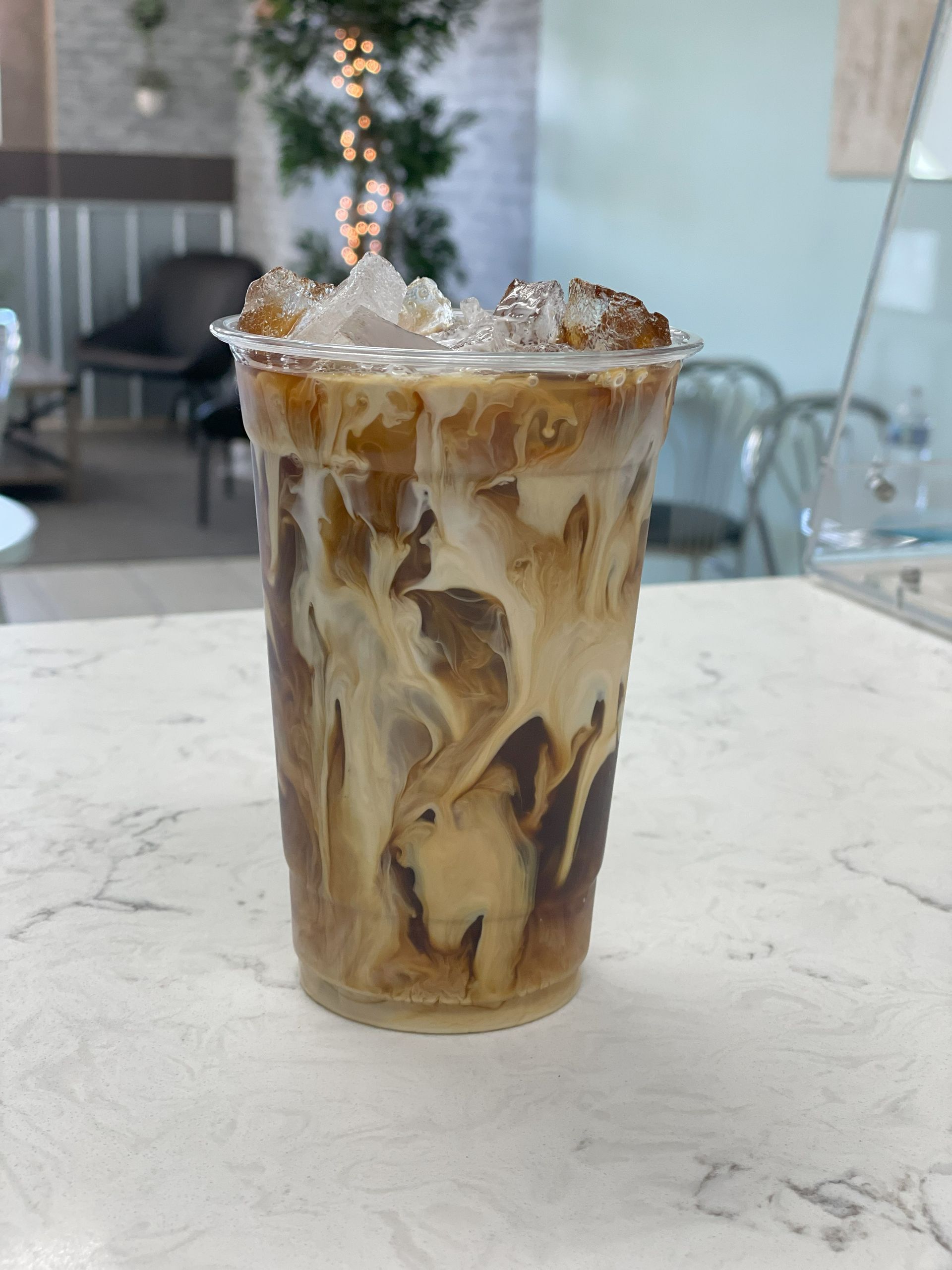 A cup of iced coffee is sitting on a counter.
