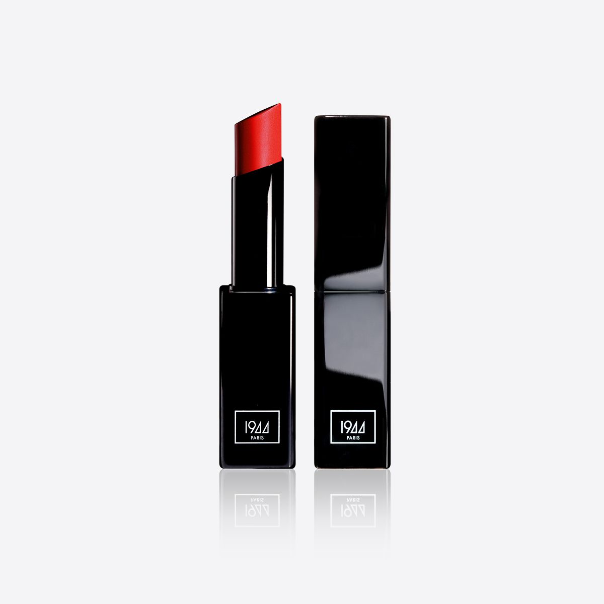 Un rouge à lèvres rouge est posé à côté d'un tube noir sur une surface blanche.
