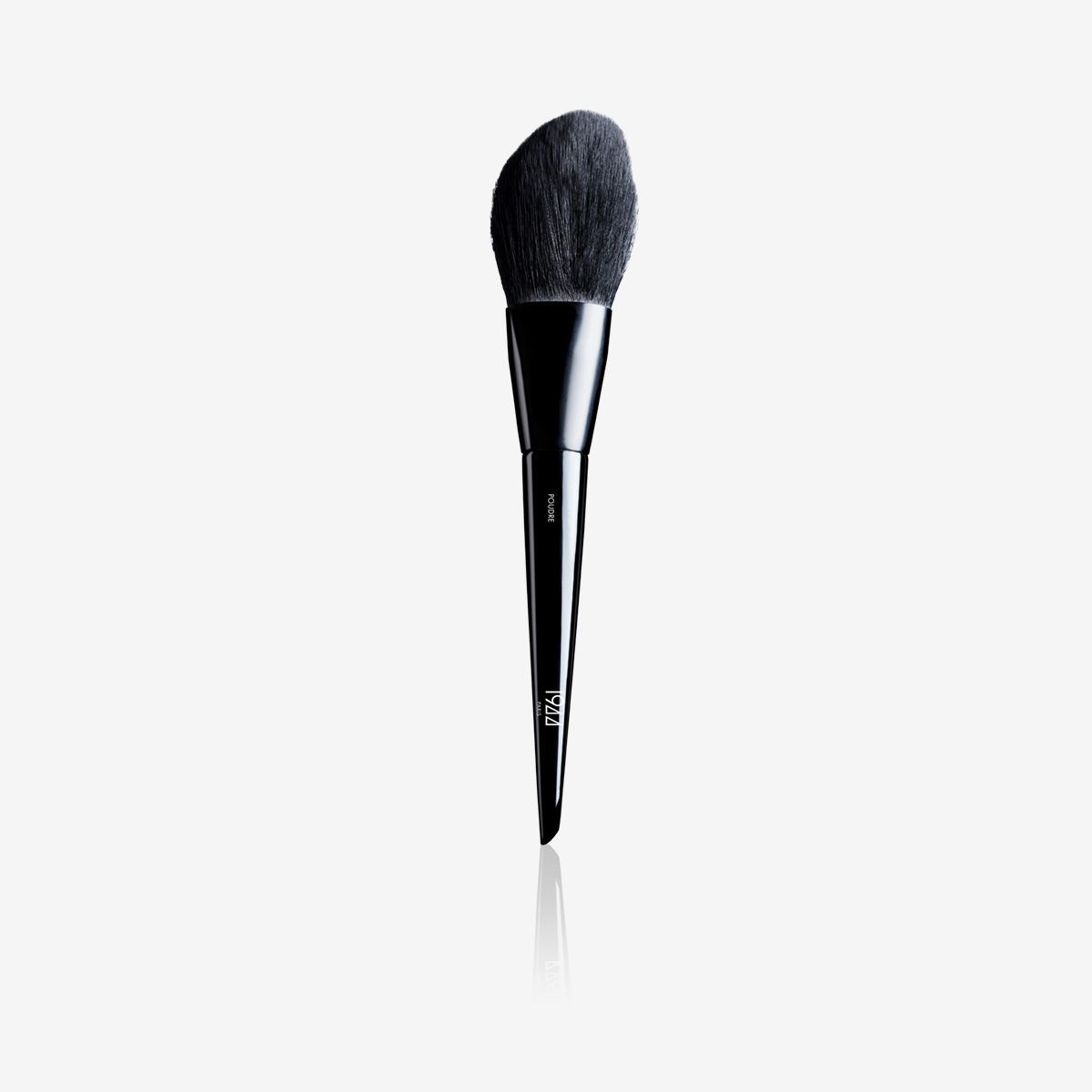Un pinceau de maquillage noir est posé sur une surface blanche.