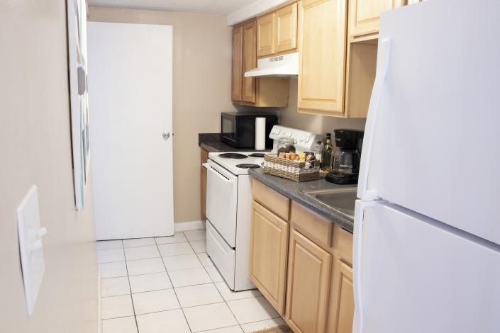 Bright kitchen with white appliances, light wood cabinets, and tiled floor