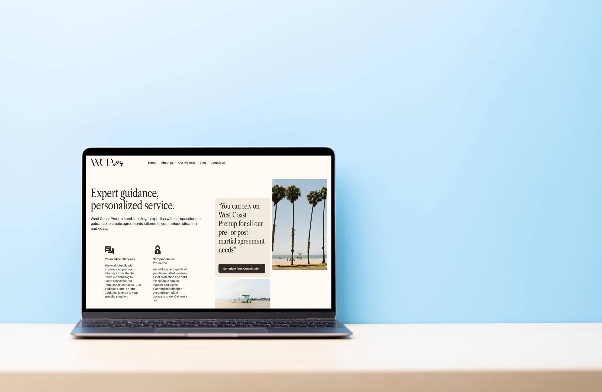 Laptop displaying a website with text and a beach photo, on a white table against a blue wall.