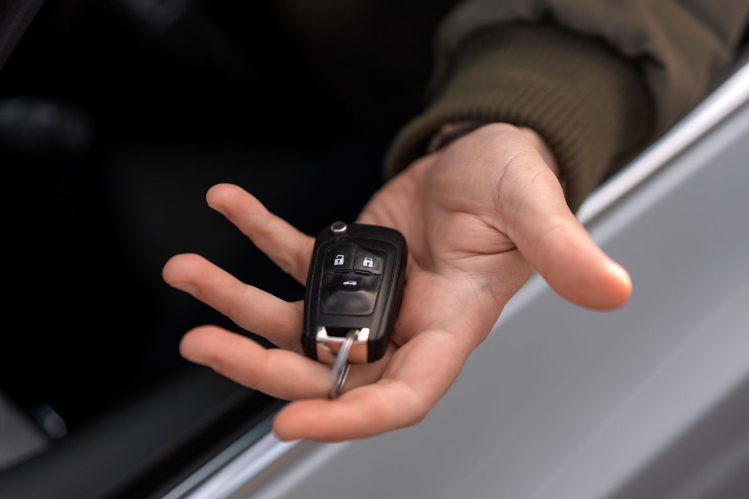A person is holding a car key in their hand.