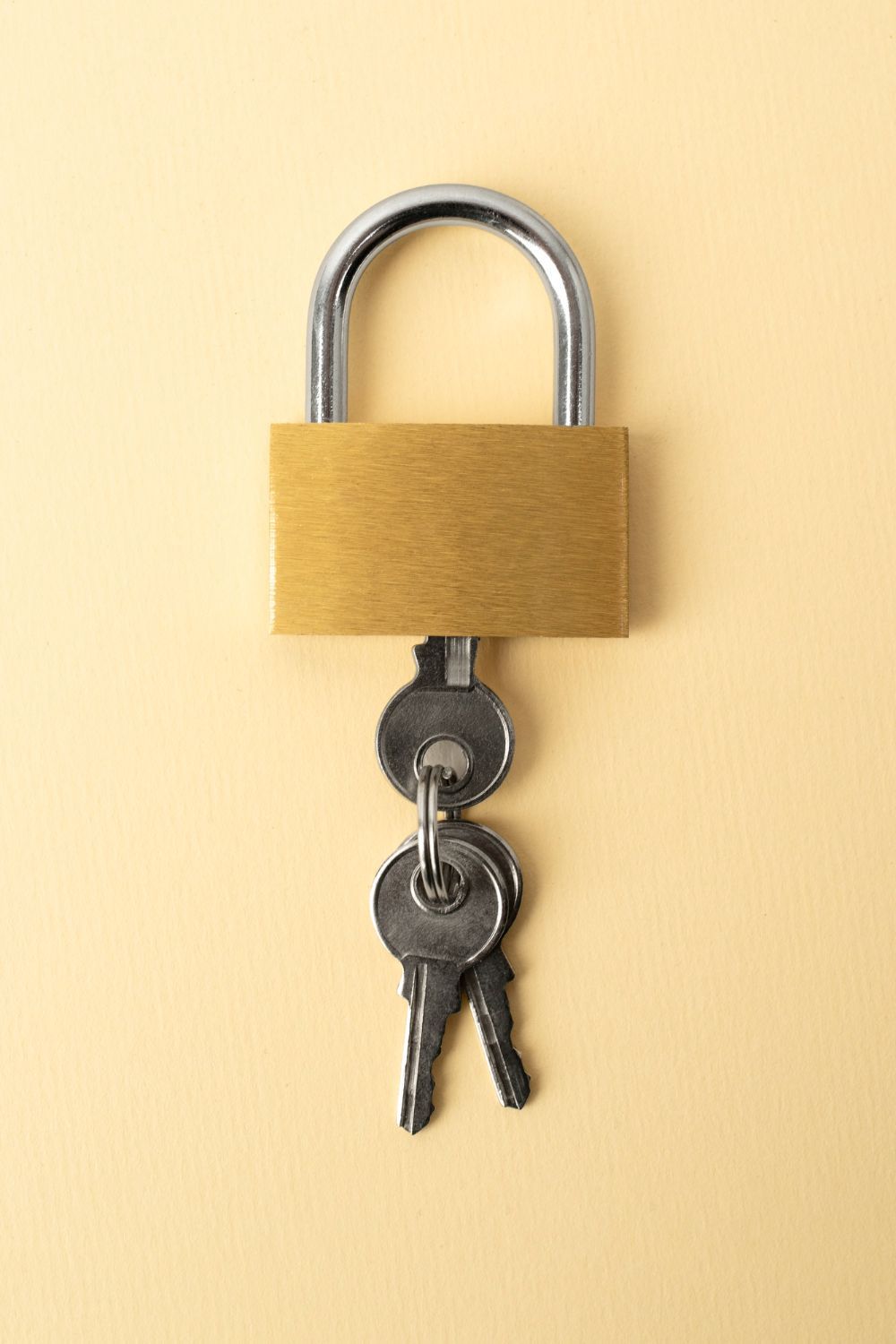 A padlock with three keys attached to it on a yellow background.