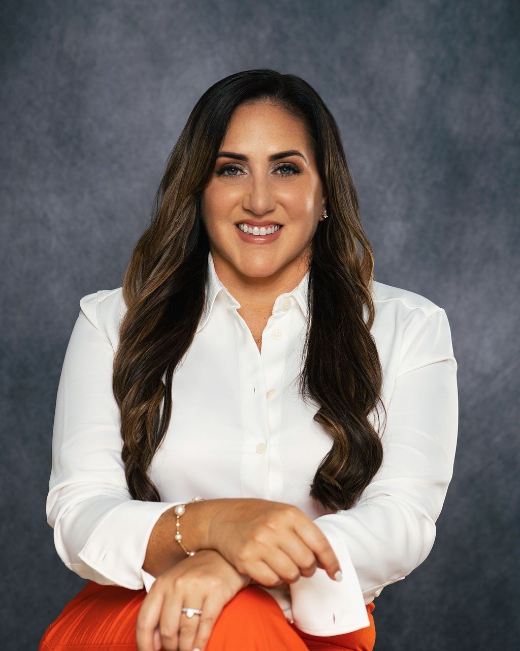 Lissette Romero in a black vest and necklace is smiling for the camera.