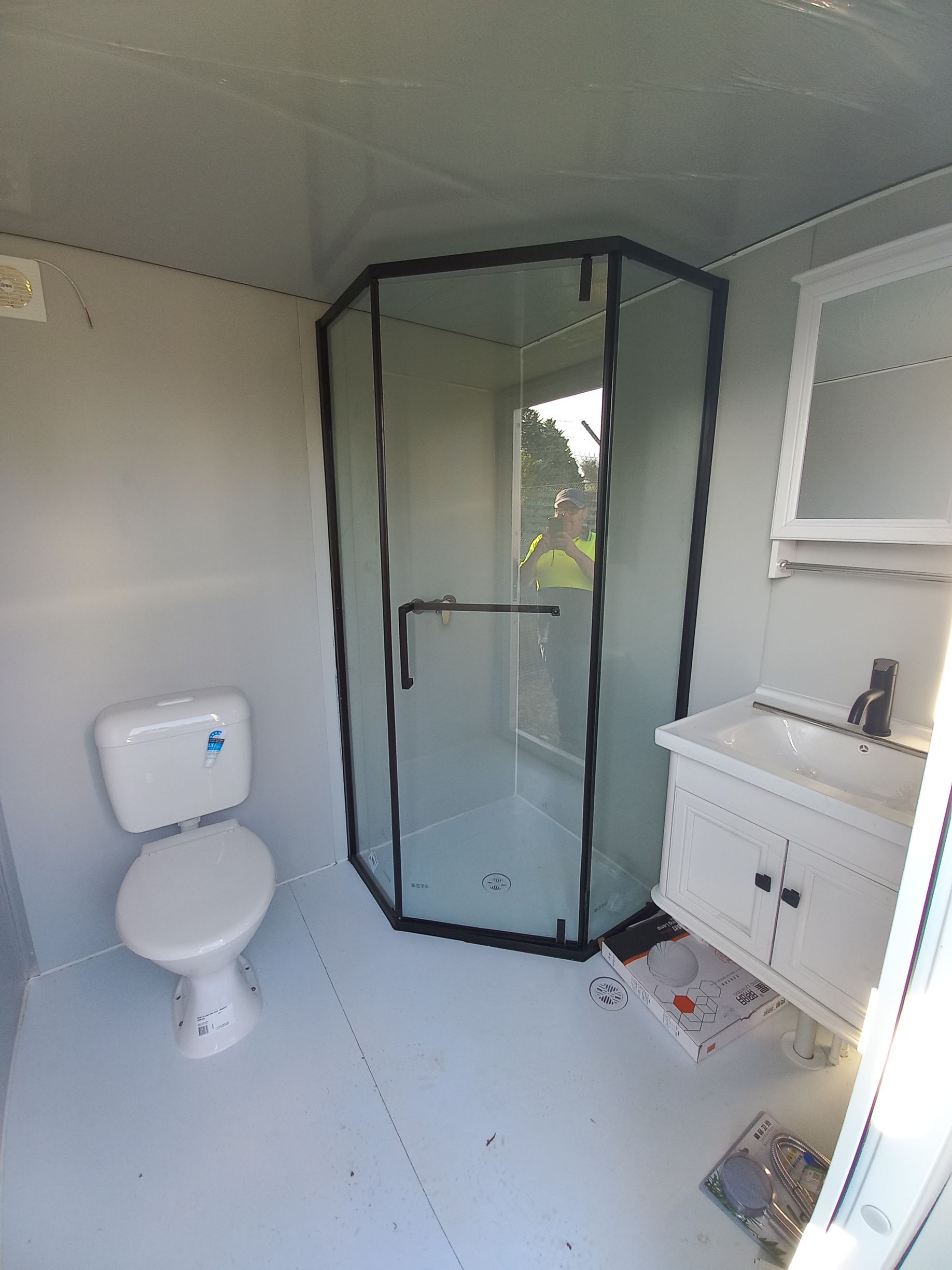 Small bathroom with a toilet, shower, and vanity. White fixtures against grey walls — Tenterfield Timber & Hardware in Tenterfield, NSW