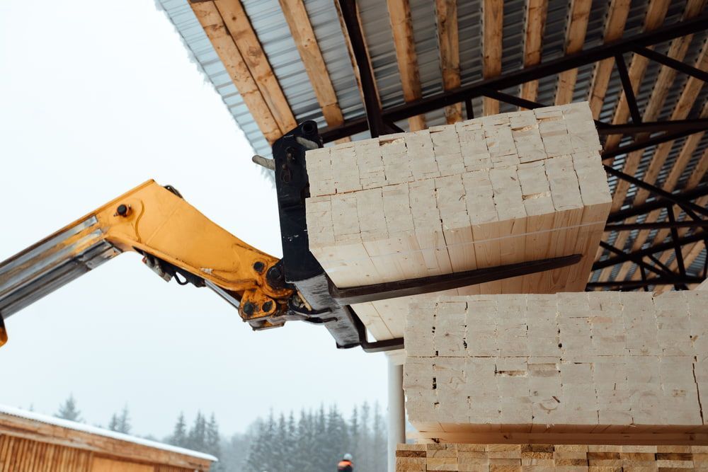 A Crane Is Lifting A Stack Of Wooden Blocks Into A Warehouse — Tenterfield Timber & Hardware in Stanthorpe, QLD