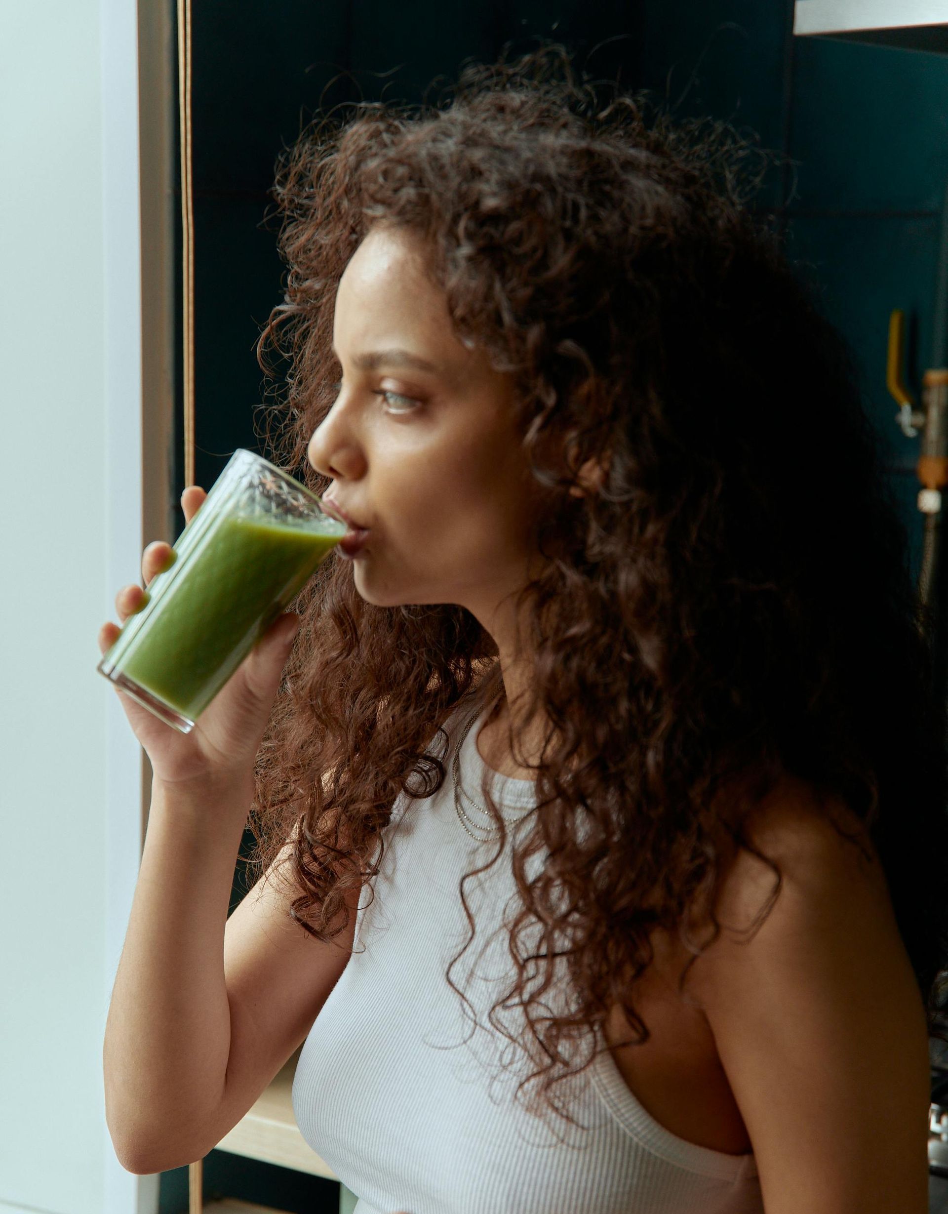 A woman is sitting at a table drinking a smoothie.