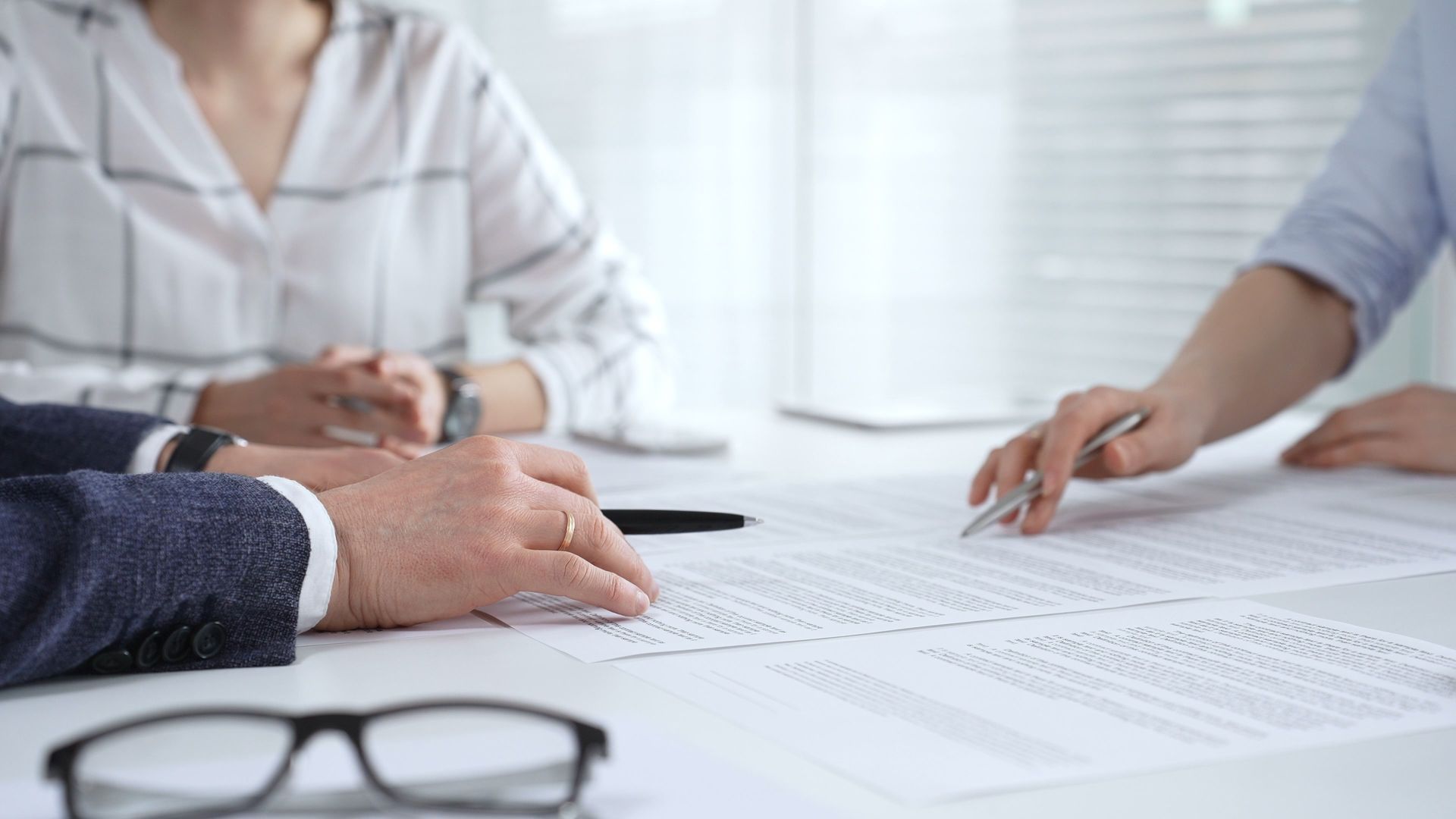 People in a bright office reviewing documents at a conference table. People in a bright office reviewing documents at a conference table.