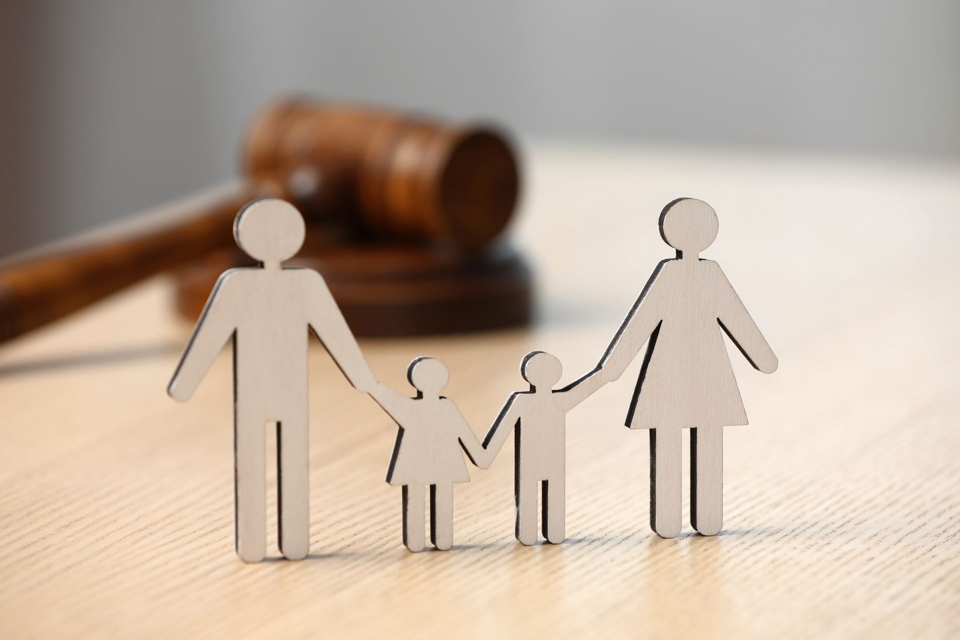 Paper family cutouts before a judge’s gavel on a wooden table Paper family cutouts before a judge’s gavel on a wooden table