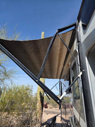 Retractable shade awning attached to a building, casting shade over a walkway in a desert setting