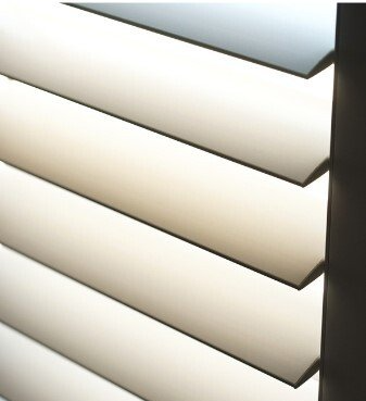 Close up of open plantation shutters with light coming through.