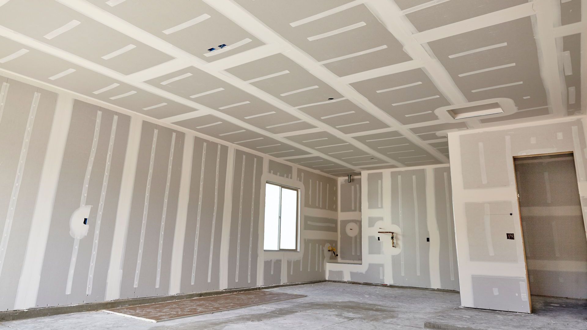 An empty room with drywall on the walls and ceiling.