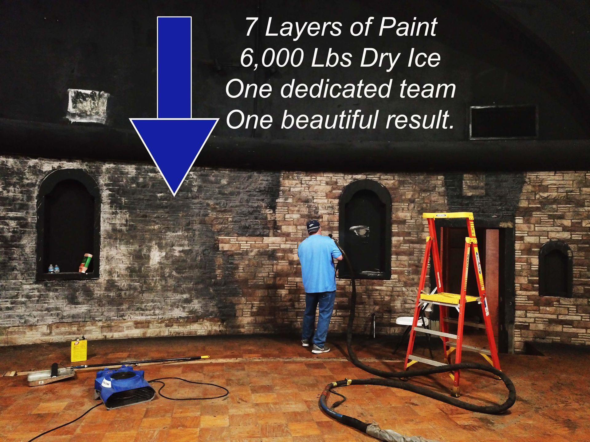 A worker uses dry ice blasting to strip paint from a brick wall, revealing the original surface underneath.