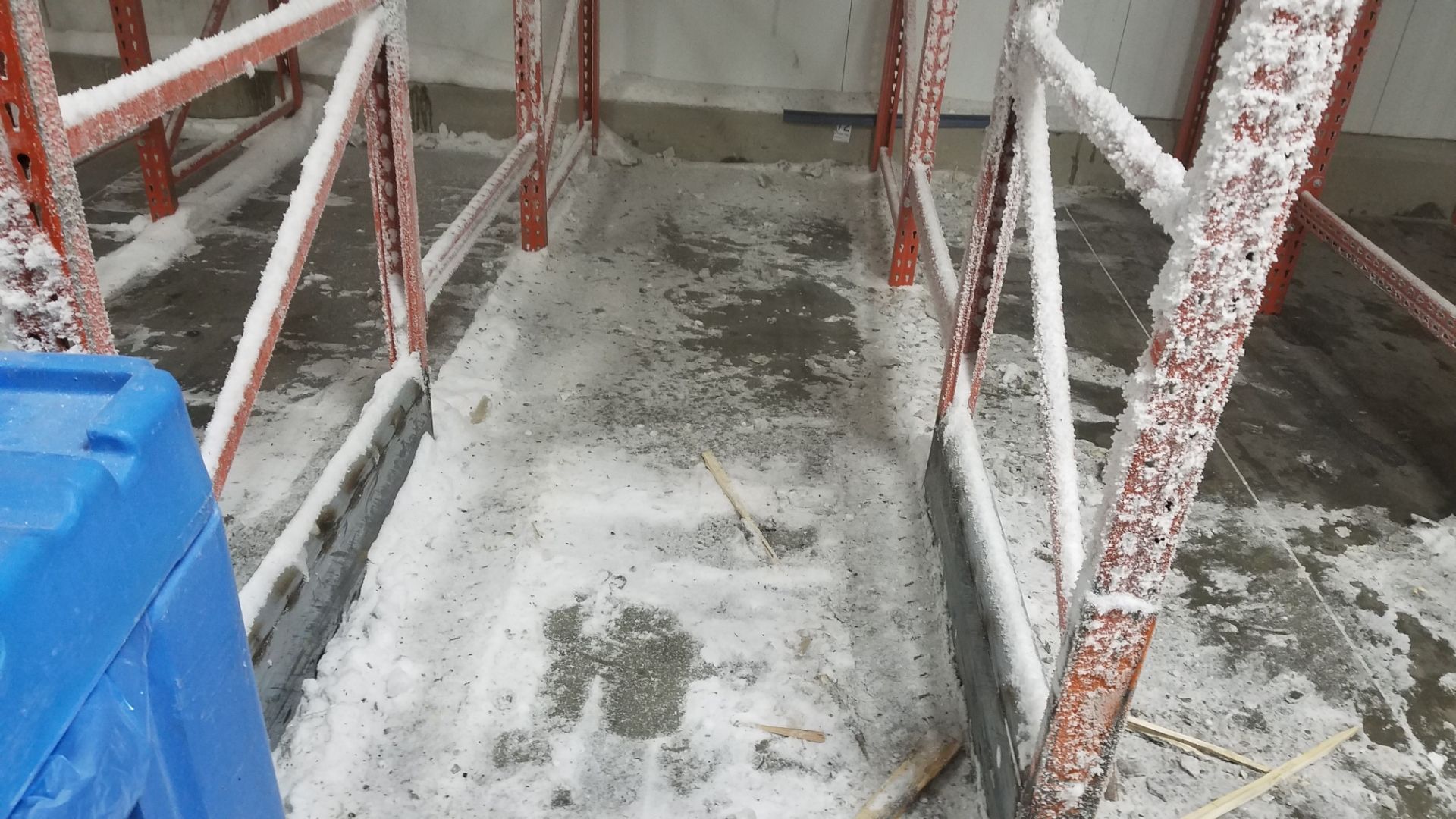 Pathway with snow-covered concrete and orange scaffolding; blue container is in the lower left corner.