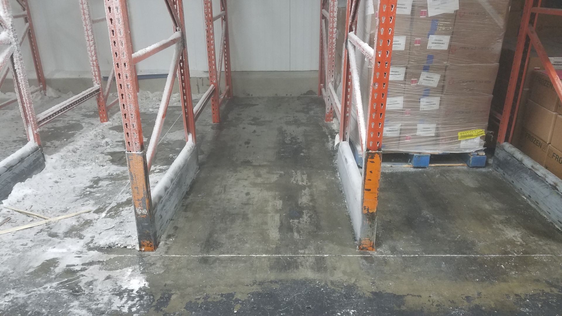 Warehouse aisle with metal shelving; concrete floor, pallets of boxes to the right.