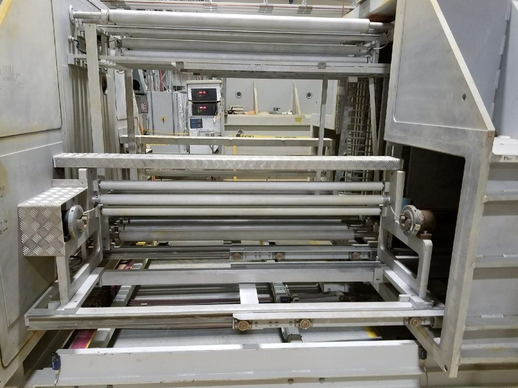 Industrial machine with rollers and metal framework, possibly for processing materials.