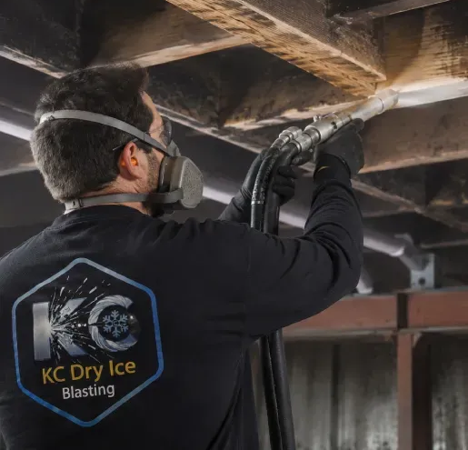 Person using dry ice blaster on a classic car in a workshop. Machine, sign with logo visible.