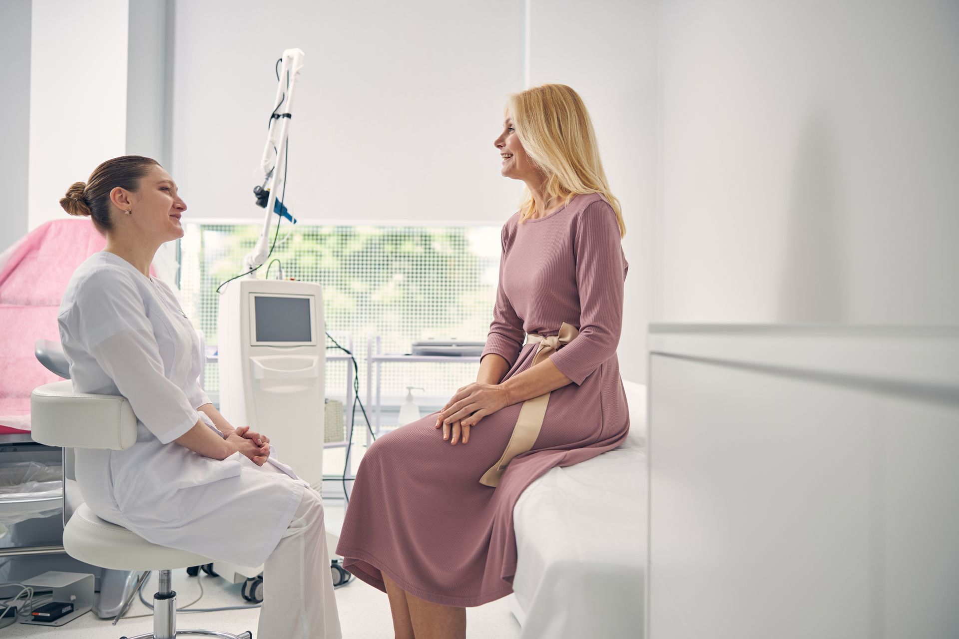 Patient seated on a clinic bed talking with a nurse beside an IV stand