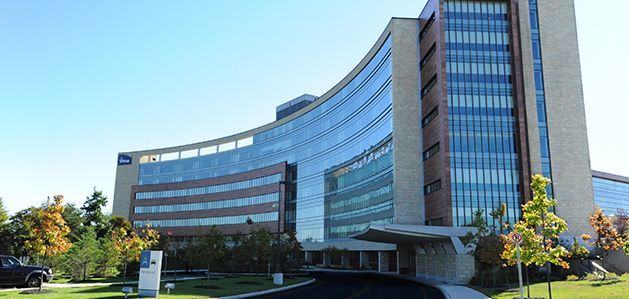 A large building with a lot of windows is surrounded by trees and grass.