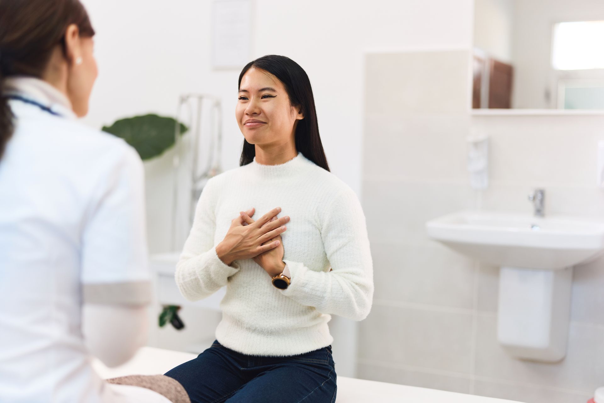 Person speaking with a doctor during a medical consultation in a bright clinic exam room