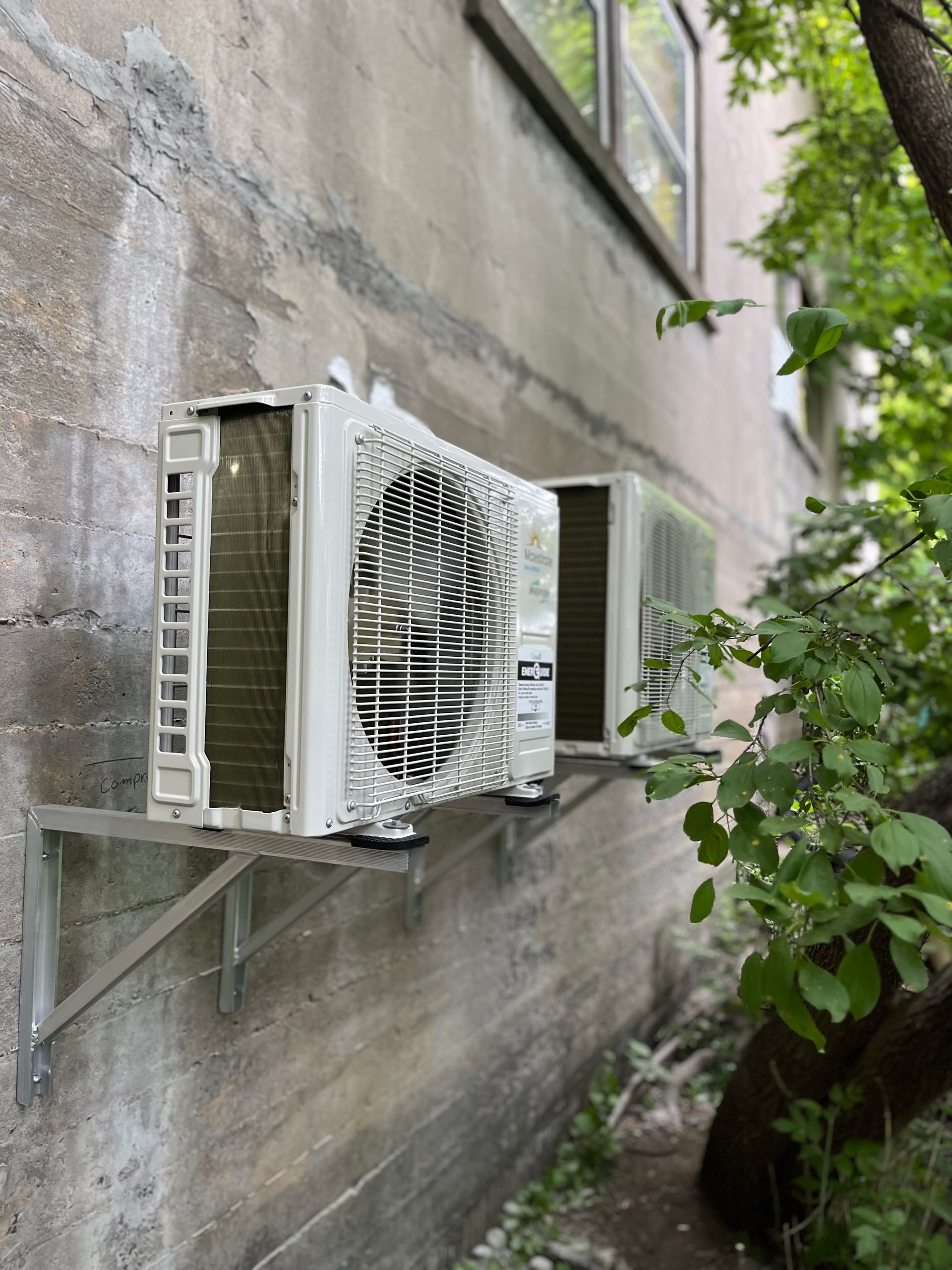 Two air conditioners are mounted on the side of a building.
