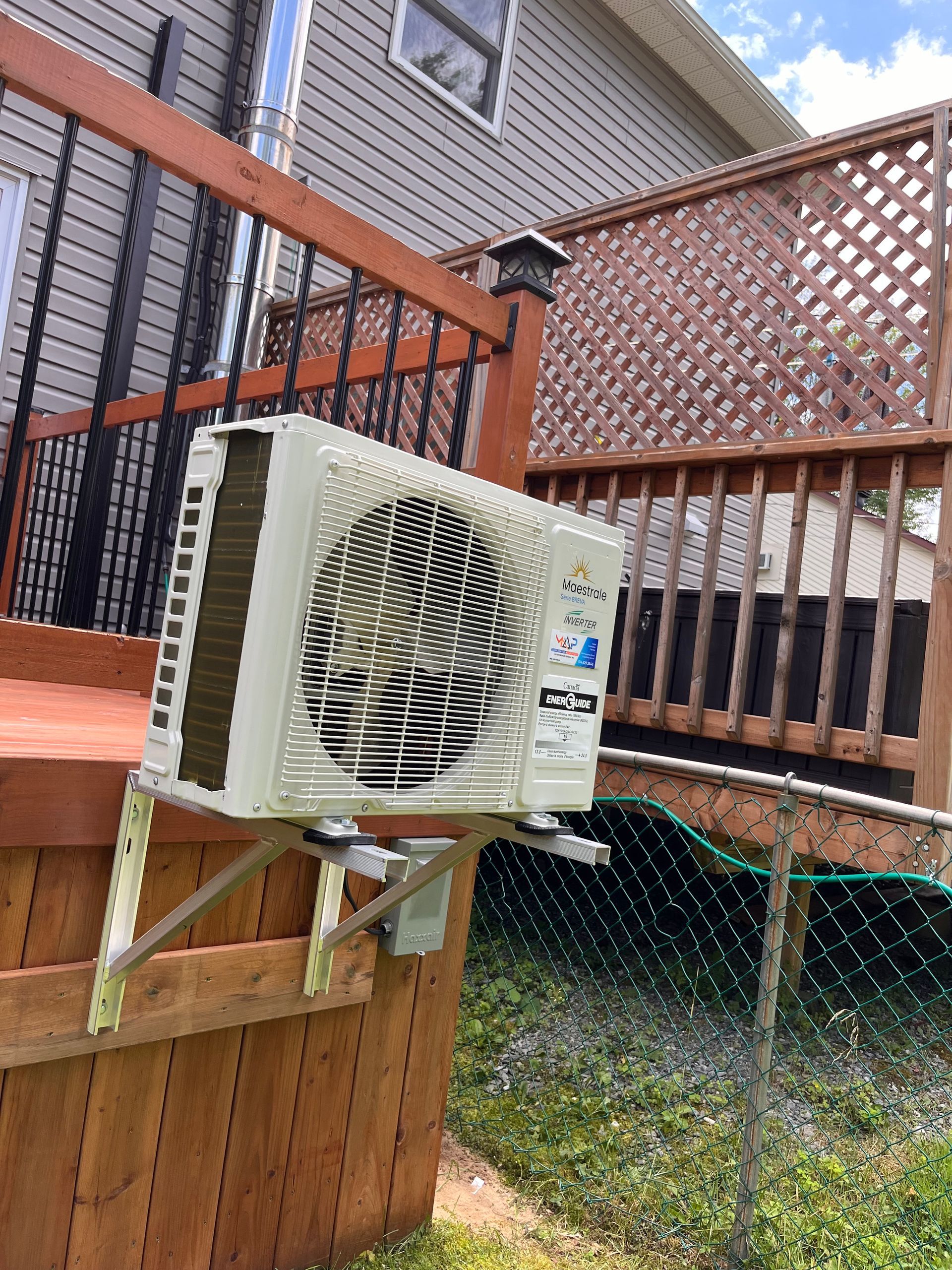Unité de climatisation montée sur une rambarde de terrasse en bois.