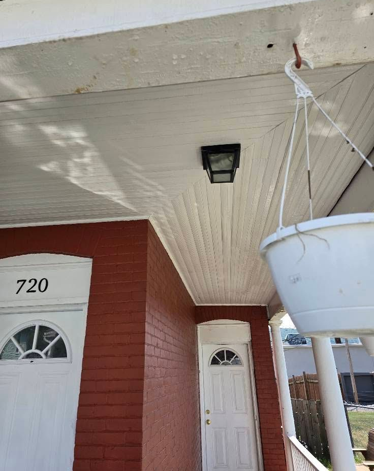 White porch ceiling with hanging planter, front doors, and house number 720 on a red brick building.