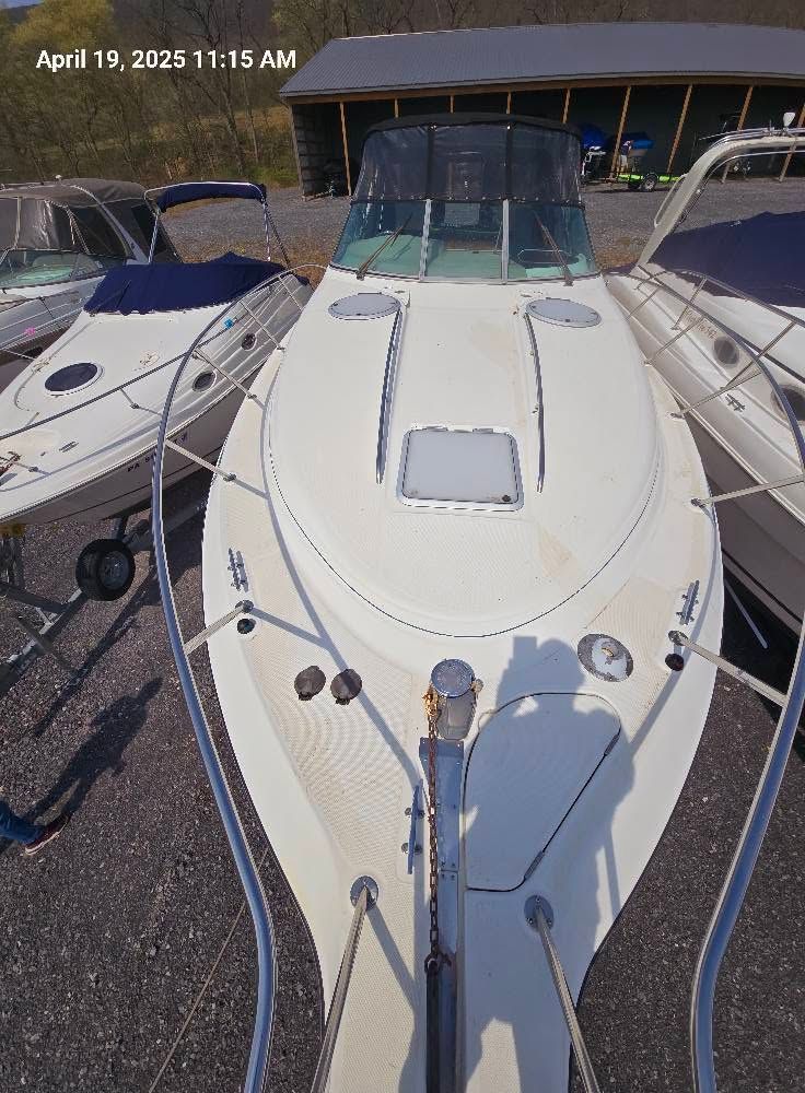 White motorboat docked beside other boats at a marina, viewed from the bow.