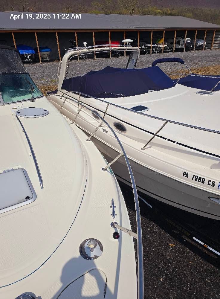 Two white motorboats tied side by side at a marina, with blue covers and railings.