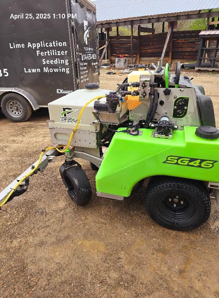 Bright green utility machine parked on muddy ground beside a work truck at a live application field demonstration.