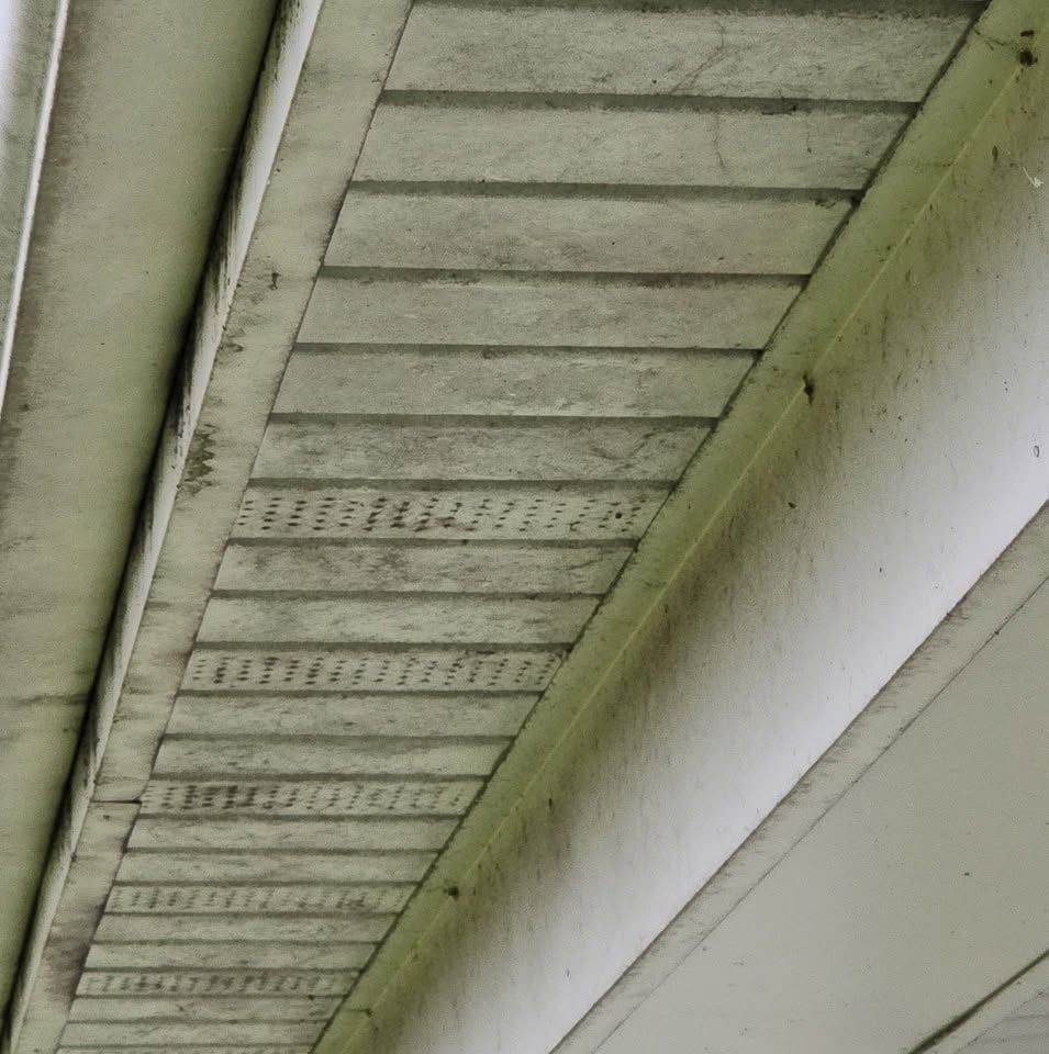 Underside of a house eave with weathered white trim and vented soffit panels