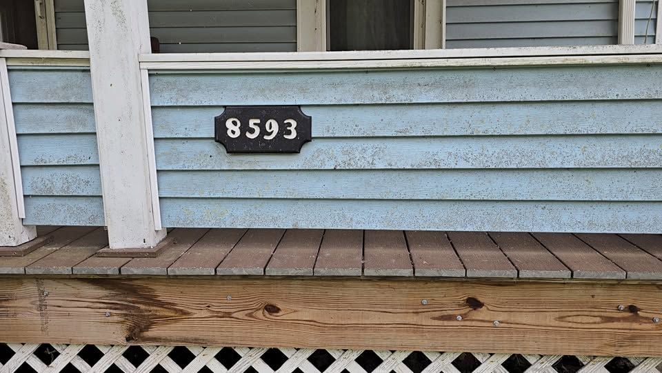 House siding with black address plaque reading 8593 above a wooden deck rail