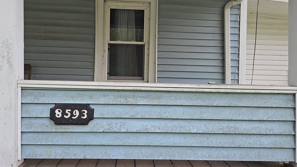 Front porch with light blue siding and house number 8593 above the railing.