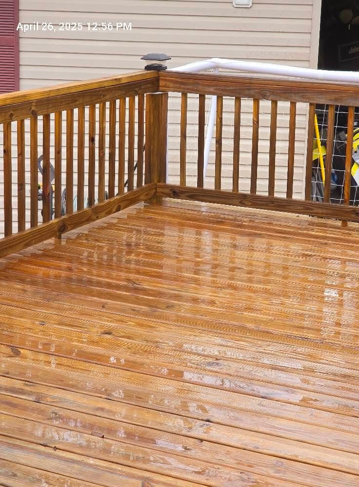 Rain-soaked wooden deck with railings beside a house, reflecting light.