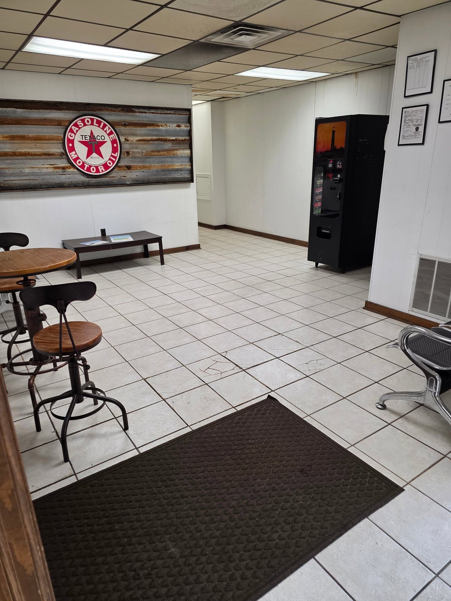Small break room with tiled floor, stools, bench seating, wall decor, and a vending machine.
