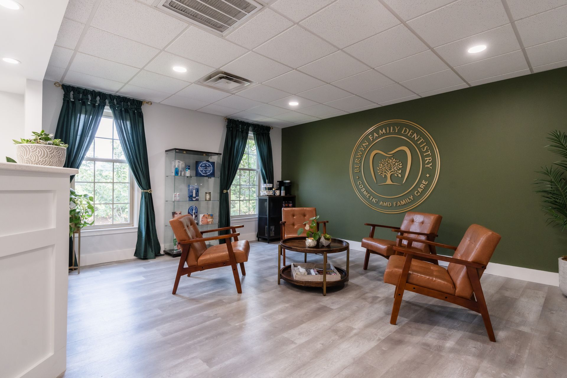Dental office waiting room with green accent wall, leather chairs, and two windows.