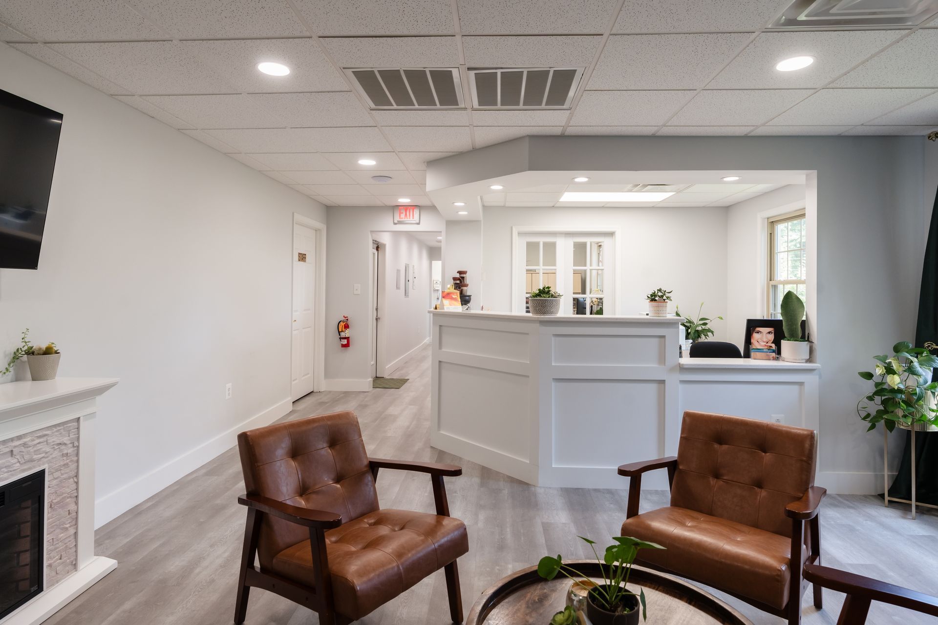 Waiting room with two brown leather armchairs, a reception desk, and a fireplace.
