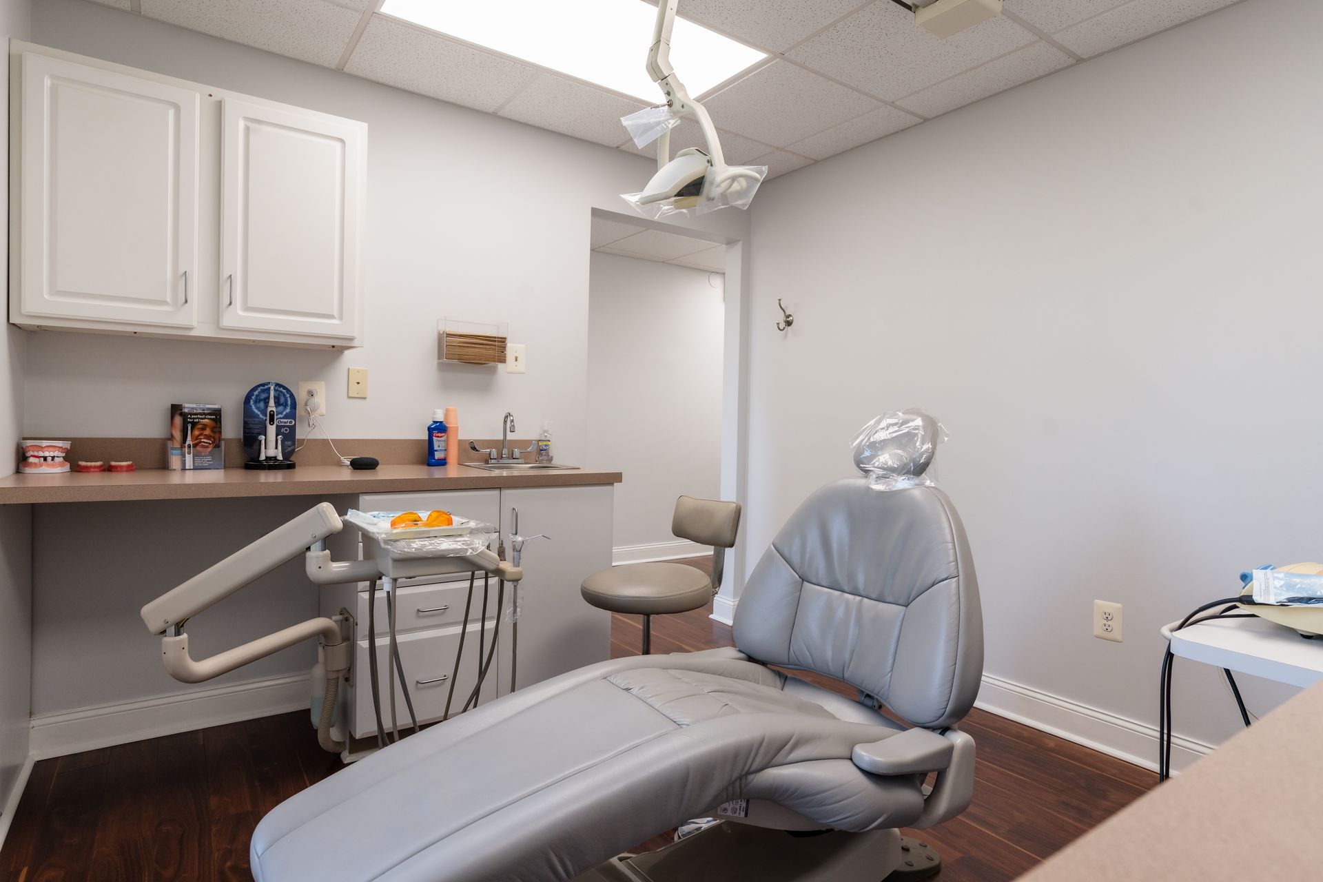 Dental exam room with a gray dental chair and cabinets.