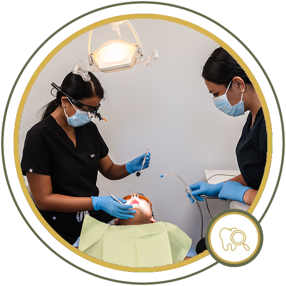 Two dental professionals working on a patient in an examination room.