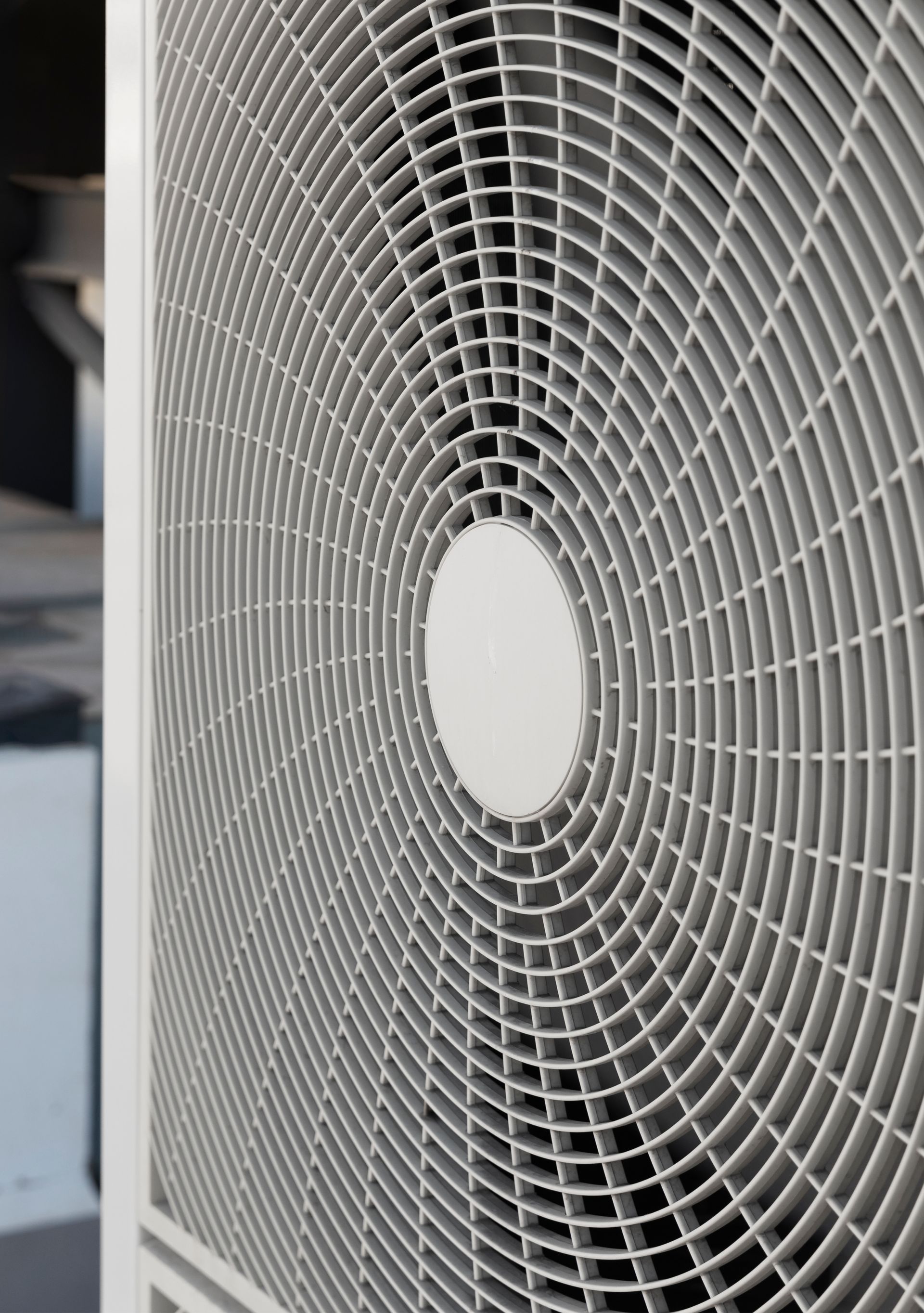 Close-up of a white circular grille with concentric metal rings, likely a fan or speaker cover.