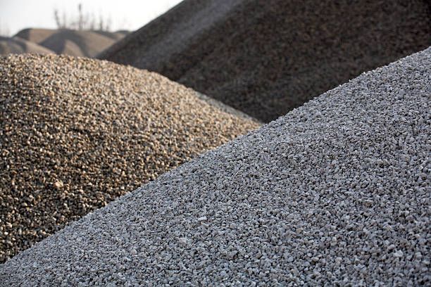 Large piles of gravel and crushed stone in gray and brown tones outdoors