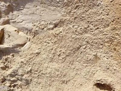 Pile of light brown sand, textured with visible grains and shadows.
