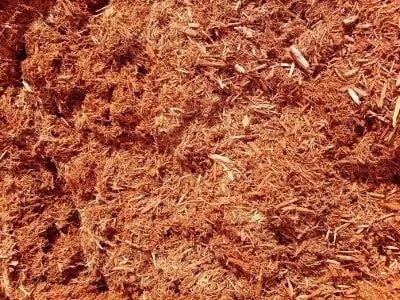 Close-up of reddish-brown shredded wood mulch, likely for landscaping purposes.